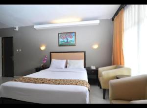 a hotel room with a bed and a chair at Hotel GRANDSARASWATI in Stasiun Poncol