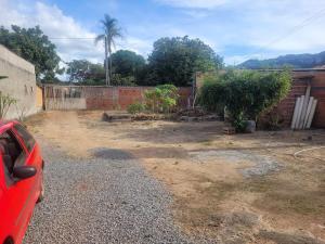 a red car parked in a yard next to a brick wall at Encanto da Rosa in Cavalcante