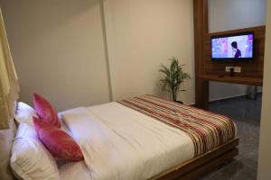 a bedroom with a bed and a tv on a wall at Hotel Rajpath Inn in Mahesāna