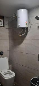 a bathroom with a toilet and a water tank on the wall at Hotel Rajpath Inn in Mahesāna