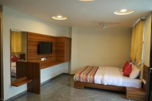 a bedroom with a bed and a flat screen tv at Hotel Rajpath Inn in Mahesāna
