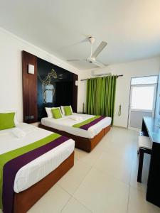 two beds in a hotel room with a piano at Seaport Negombo in Negombo