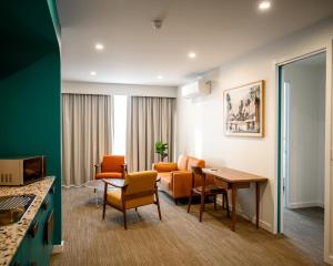 a room with a table and chairs and a couch at Peninsula Hotel Motel in Adelaide