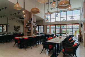 a dining room with tables and chairs and windows at Love Rawai Hotel in Rawai Beach