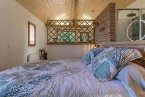 a bedroom with a bed with a blue comforter at Le cabanon in Mauressac