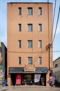 a tall brick building with a sign in front of it at ライズ 2人部屋 か4人部屋 in Kasugai