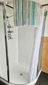 a shower with a glass door and a curtain at Waterscape Floating Apartment in Augusta