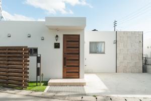 a white house with a wooden door on a street at Value Residence Hotel 久貝 in Miyako-jima