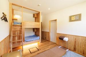 a room with wooden walls and bunk beds at 宿と図書サロン 花車 Hanagurum Inn in Amakusa