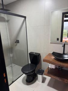 a bathroom with a black toilet and a shower at Refúgio do Morro - Cabana 1 in Torres