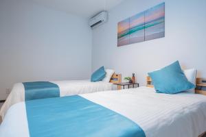 two beds in a room with blue and white at Value Residence Hotel 久貝 in Miyako-jima