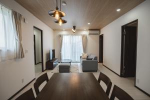 a living room with a wooden table and chairs at Value Residence Hotel 久貝 in Miyako-jima