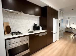 a kitchen with black cabinets and a sink and a stove at Mega Style Apartments Tribeca in Melbourne