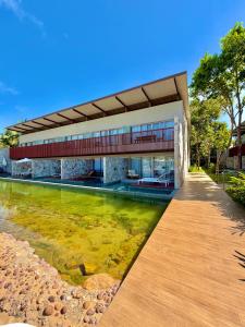 a house with a pond in front of it at Île Lumière in Pipa