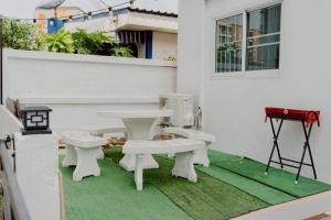 a patio with white benches and a table and a grill at ชรินพูลวิลล่าบางแสน Sunflower Villa Bangsaen Wangmuk in Ban Rong Khoei
