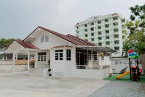 a white house with a playground in front of a building at ชรินพูลวิลล่าบางแสน Aurora Villa Bangsaen natedee road in Chon Buri