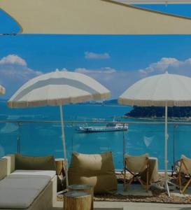two umbrellas and chairs on a beach with the ocean at Ocean View Hotel near Incheon Airport in Chagyak-to