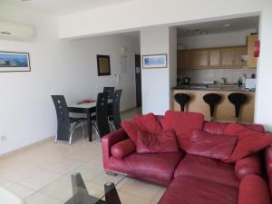 a living room with a red couch and a kitchen at Melania Apartment in Paphos City