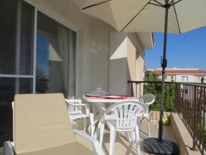 a white table and chairs on a balcony with an umbrella at Melania Apartment in Paphos City