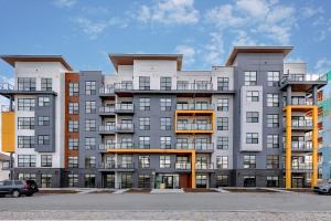 a large apartment building with a parking lot at Family Stylish 1BR and Den Condo -Apartment with City View, Downtown, Balcony, Free Parking, In-Suite Laundry! in Calgary