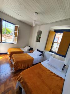 a room with three beds and two windows at Pouso History in Ouro Preto