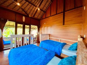 two beds in a room with wooden walls at Blind Dog Inn in Sanur +37 photos