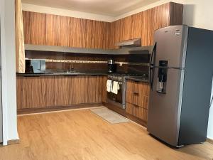 eine Küche mit Edelstahlkühlschrank und Holzschränken in der Unterkunft Casa Luma in Aguascalientes
