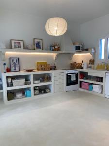 a kitchen with white cabinets and a pendant light at Lobster House Antiparos in Antiparos +23 photos