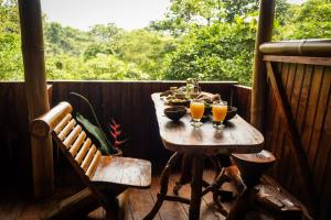 a table with two glasses of orange juice on a porch at Toucan Lodge Amazon Rainforest Retreat in Tarqui