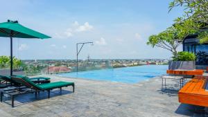 a swimming pool with chairs and a green umbrella at Wyndham Opi Hotel Palembang in Palembang