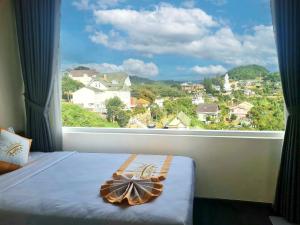 a bed with a large window with a view of a city at Aurora Hotel Đà Lạt in Da Lat