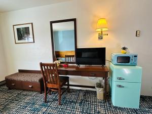 a hotel room with a desk with a microwave and a television at Curly Redwood Lodge in Crescent City +53 photos