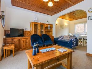 a living room with a blue couch and a tv at Min Y Traeth in Amlwch