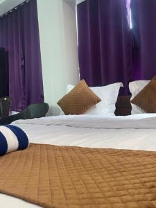 a bedroom with a large bed with purple curtains at Vista Maria Guesthouse in Dona Paula