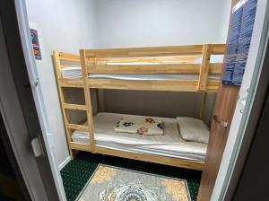 a wooden bunk bed in a small room at Pulse capsule hotel in Almaty