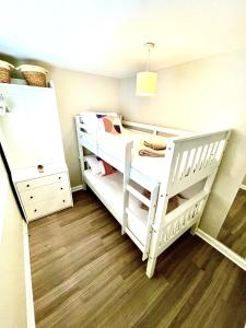 a bedroom with two bunk beds and a wooden floor at Harbour Hideaway, Porthleven in Porthleven