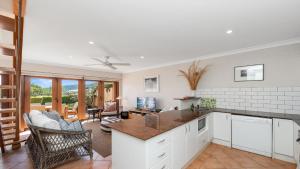 a kitchen with white cabinets and a living room at 'Marina Bay View' by HolidayCo in Killcare +16 photos