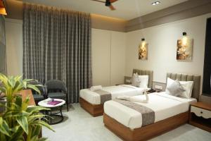 a hotel room with two beds and a table at Hotel Regency Grand in Shikrapur