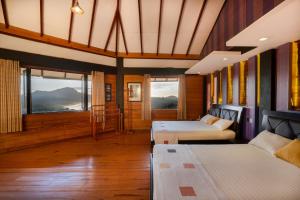 a room with two beds and windows with mountains at Amansara Bungalow - Panoramic Lake View Villa, Nuwara Eliya in Nuwara Eliya