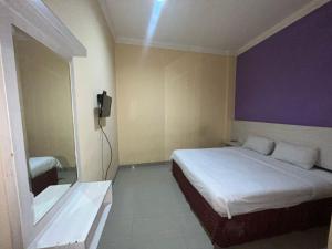 a bedroom with a bed and a tv on the wall at Hotel Alden in Makassar