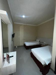 a hotel room with two beds and a mirror at Hotel Alden in Makassar +3 photos