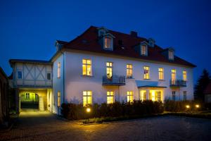 ein großes weißes Haus mit nachts eingeschaltetem Licht in der Unterkunft Appartements Residenz Jacobs in Ballenstedt