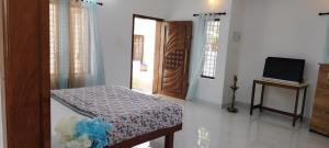 a bedroom with a bed and a tv and a door at Temple House in Trivandrum