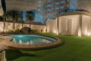 a swimming pool in the middle of a lawn with a building at White House, Billiard, Private Pool, Prime Location in Angeles