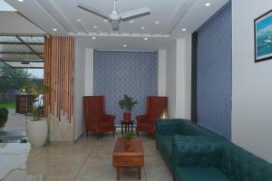 a lobby with a green couch and red chairs at Click Collection The Abode Dharamshala in Dharamshala