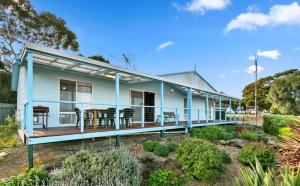 a blue house with a deck with a table and chairs at Blue Lagoon in American River