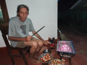 a man sitting in a chair with a spear and food at Villa iSoNet in Weligama