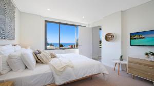 a white bedroom with a large bed and a window at Oceans Edge #7 Accom Holidays in Terrigal