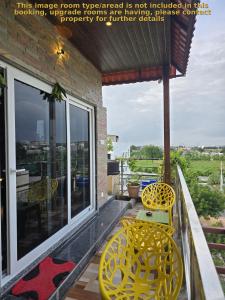a balcony with two yellow chairs and a table at Barla's Home Stay - Mini Studio Room in Shamshabad