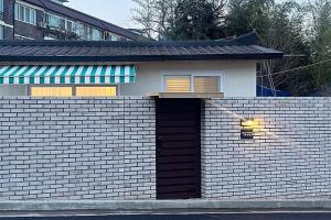 a small house with a brick wall with a door at Jeonju One Two Stay in Jeonju